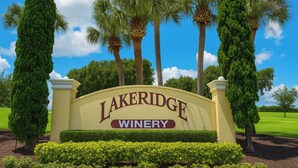 Un panneau indiquant le domaine viticole de Lakeridge, entouré de grands arbres et surplombé par un ciel bleu clair.