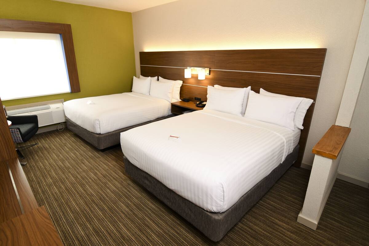 Una habitación de hotel con dos camas, un escritorio y una mesita de noche.