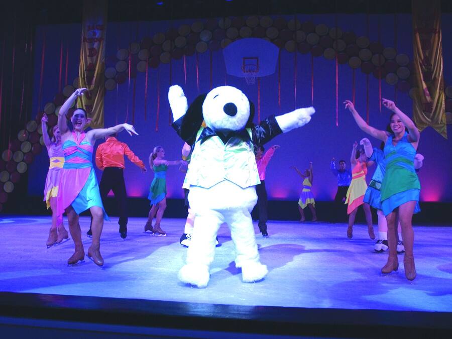 Un escenario con un personaje publicitario y bailarines actuando.