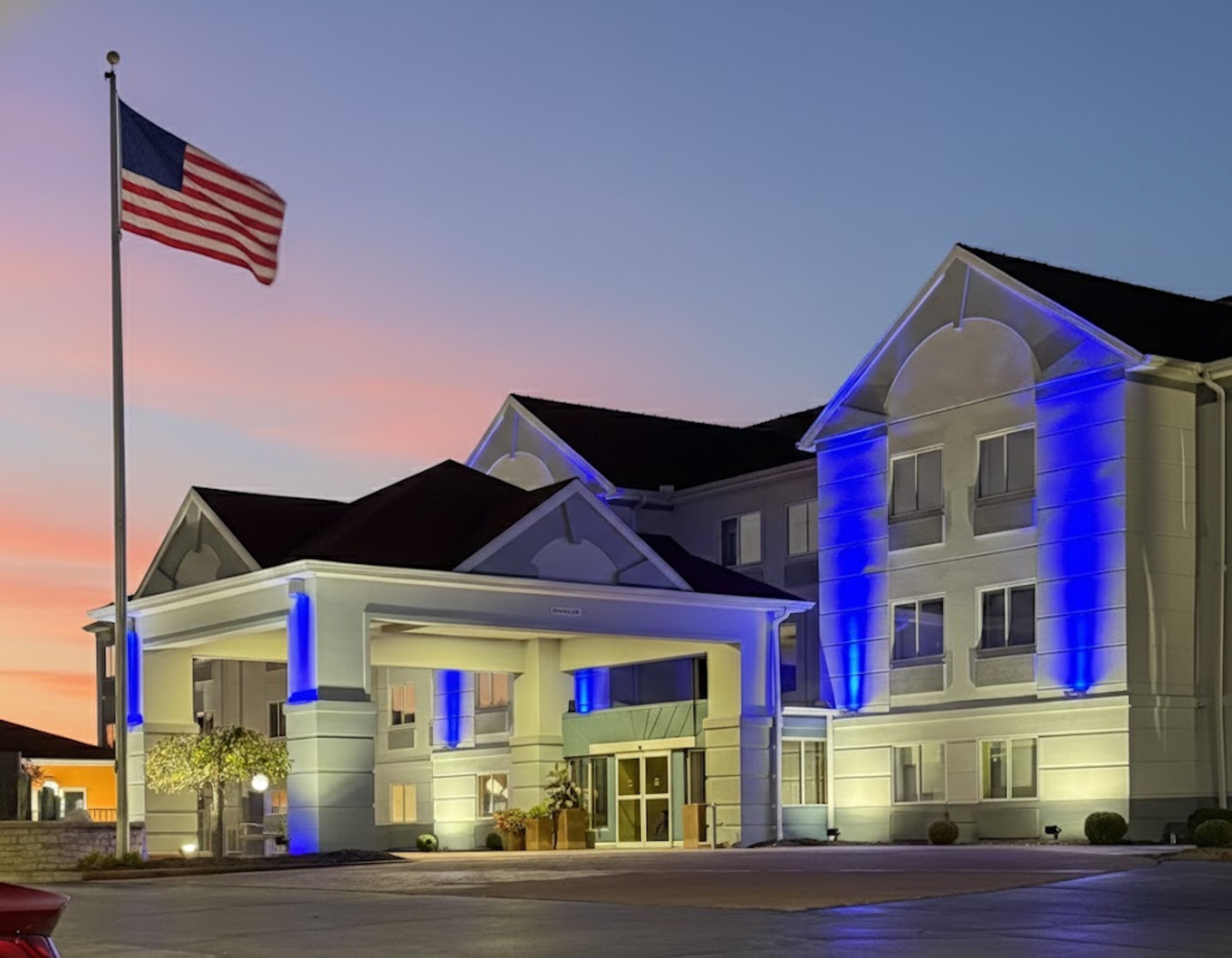 A hotel with a large entrance and a flagpole with an American flag.
