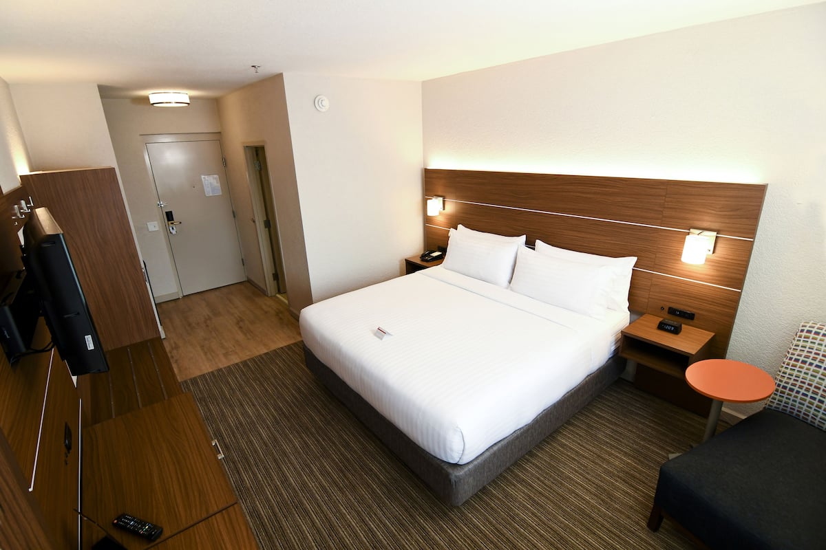 Una habitación de hotel con una cama grande, mesitas de noche, un escritorio y una silla.