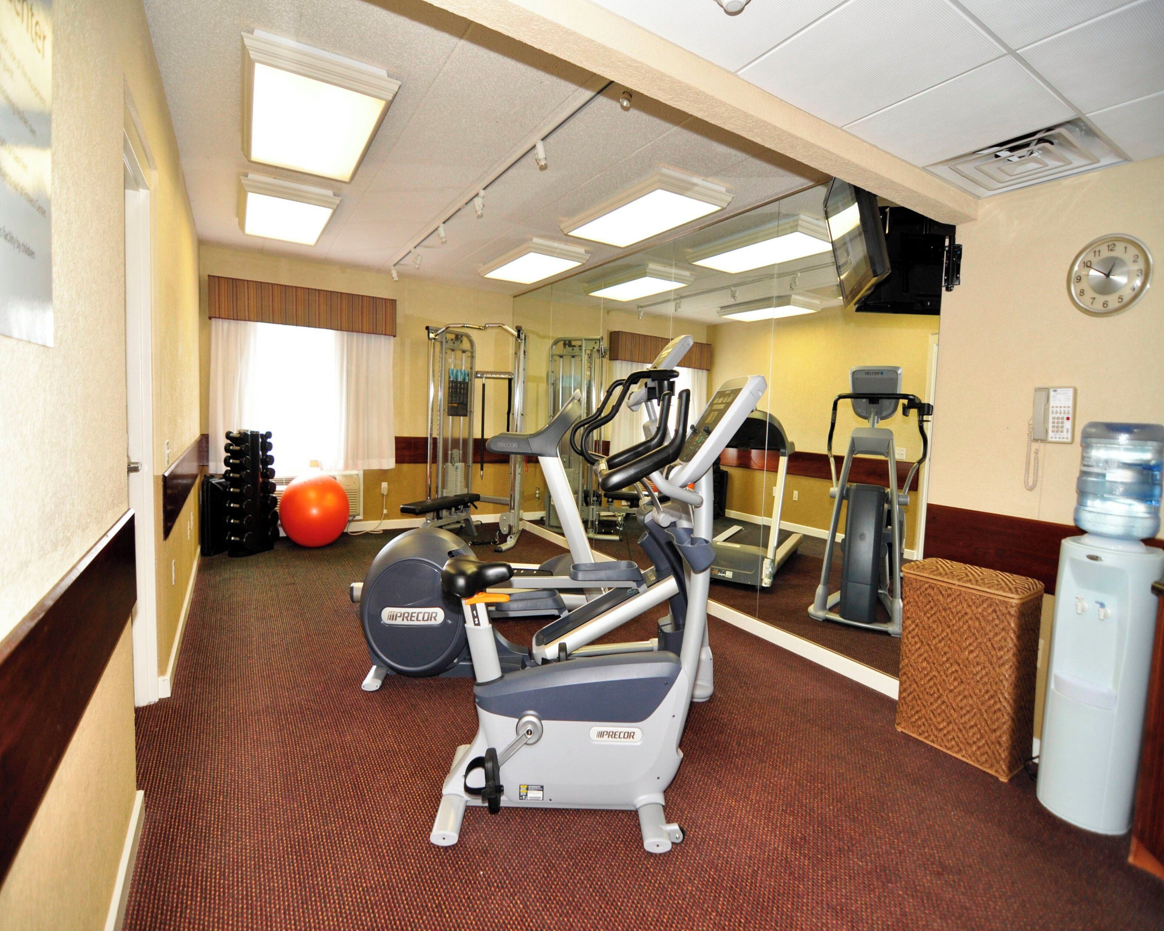 A gym with exercise equipment, a water dispenser, and a clock on the wall.