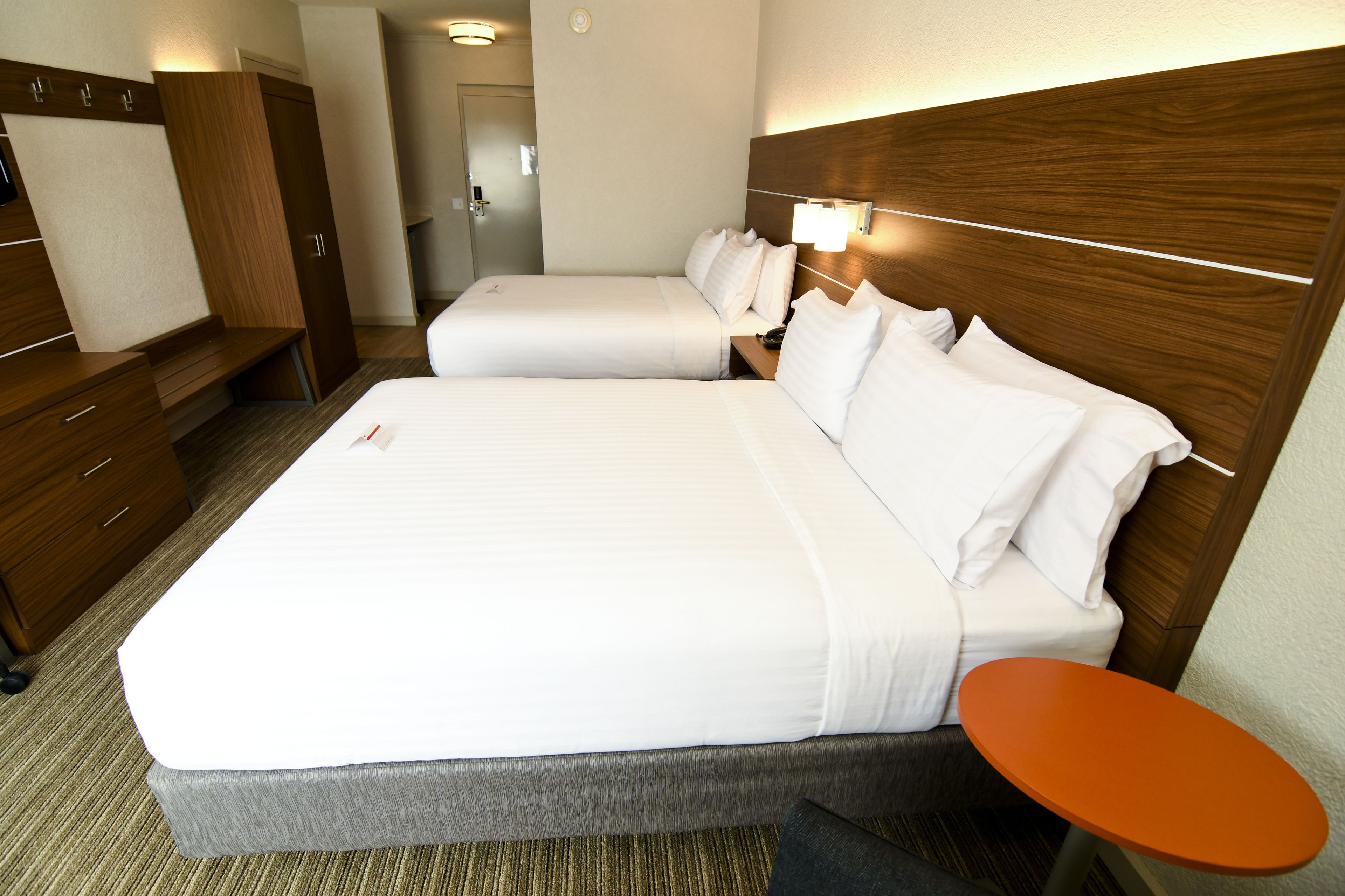 Una habitación de hotel con una cama grande, una mesita de noche, un armario y la puerta del baño.