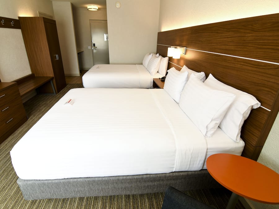 Una habitación de hotel con una cama grande, una mesita de noche, un armario y la puerta del baño.
