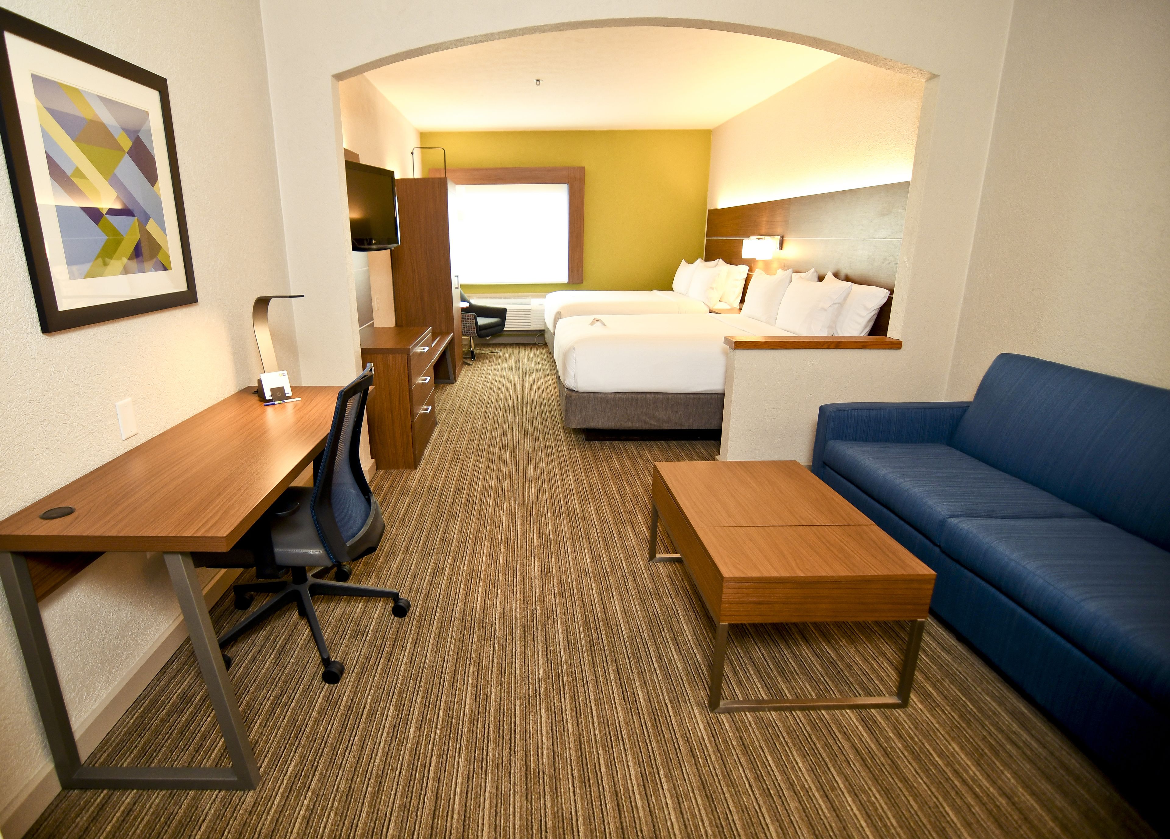 Una habitación de hotel con cama, escritorio, sillón, sofá y televisión.