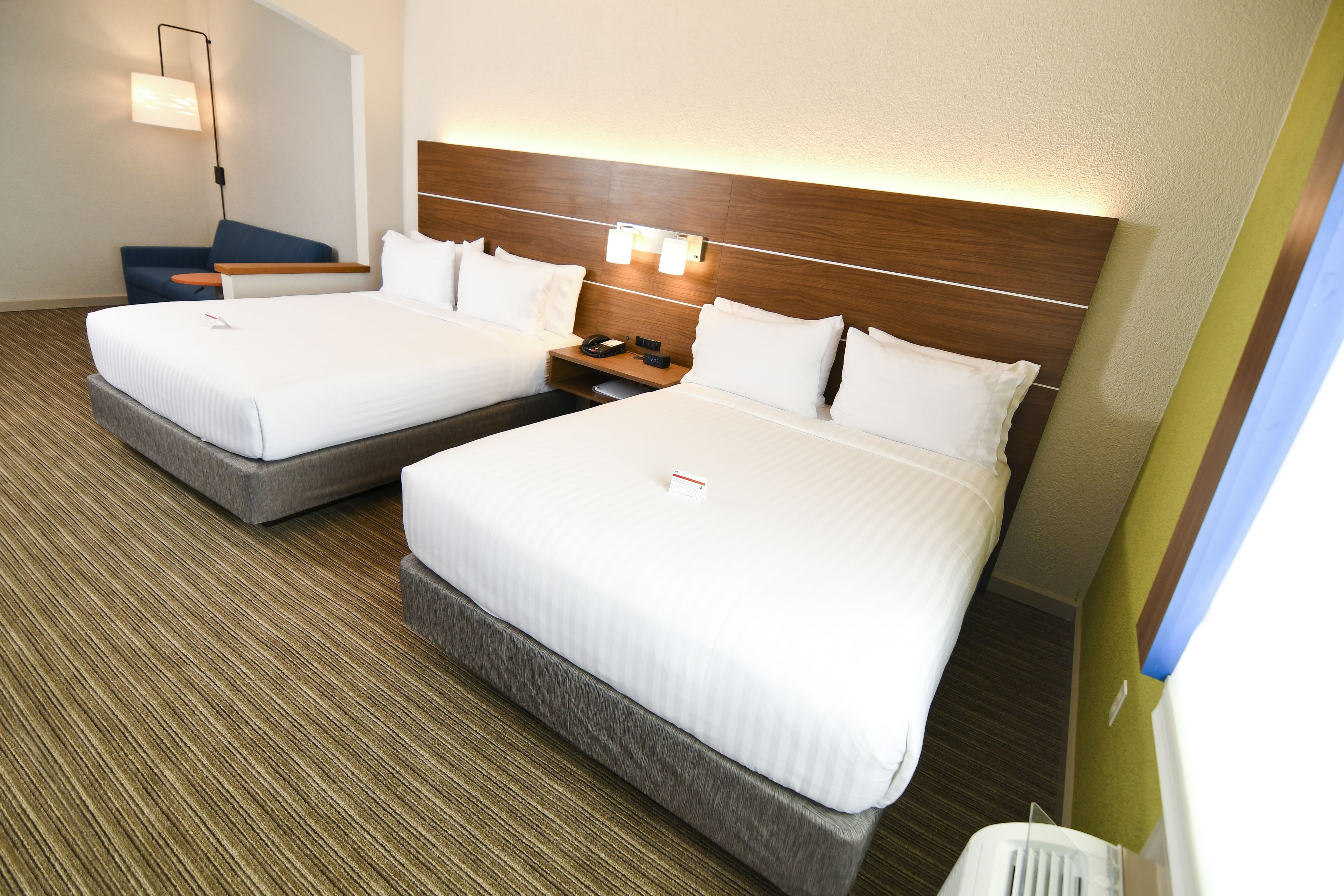 Ett hotellrum med två sängar, ett sängbord med en lampa och en modern design.