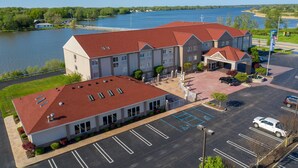 A hotel with a red roof, a parking lot, and a view of a lake. - Holiday Inn Express Hotel & Stes Port Clinton-Catawba Island by IHG (Port Clinton)