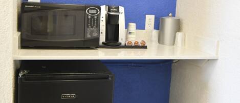 A kitchenette with a microwave, coffee maker, and a refrigerator.