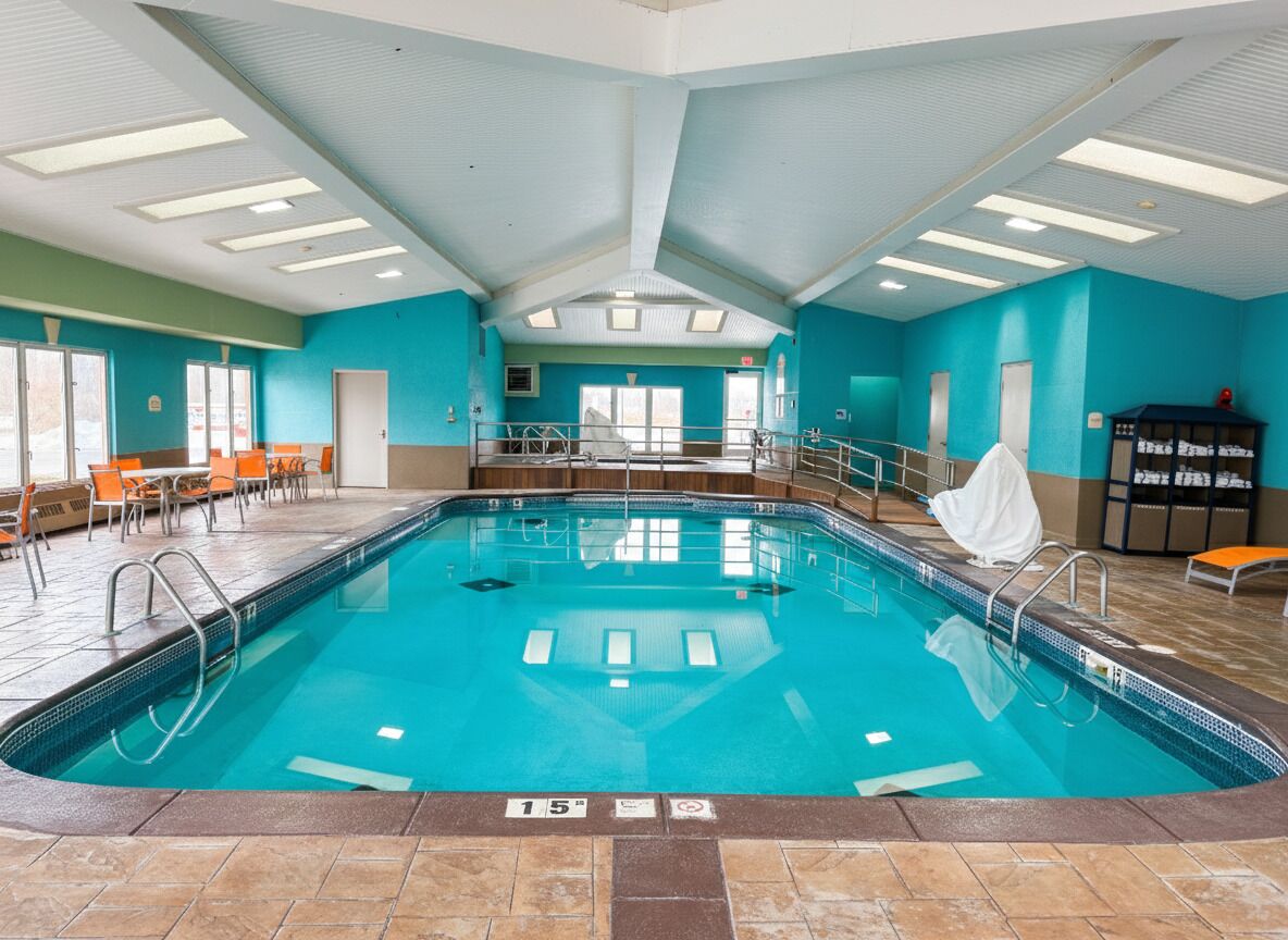 An indoor swimming pool with clear lane markings, a tiled floor, and a ceiling with skylights.