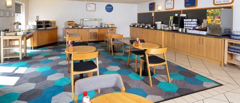 Area colazione con tavoli, sedie e un banco buffet.