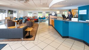 A modern hotel lobby with a reception desk, seating area, and a bar. - Holiday Inn Express Gloucester - South by IHG (Gloucester)