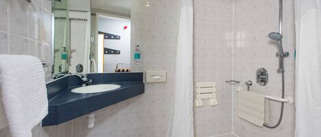 Un baño moderno con lavamanos, espejo, ducha y toallero.