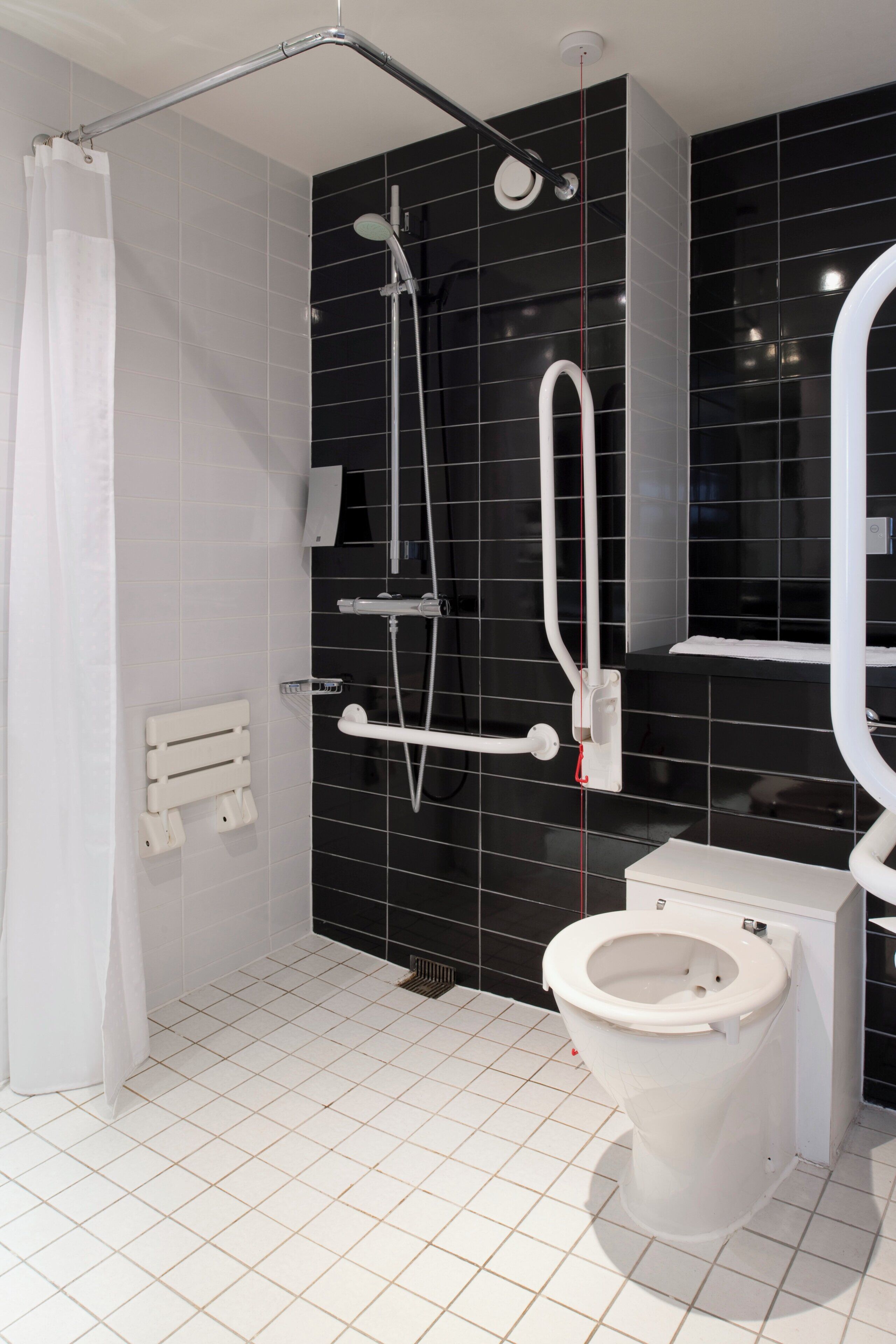 A modern bathroom with a white toilet, a shower with a handheld showerhead, and a glass-enclosed shower stall.