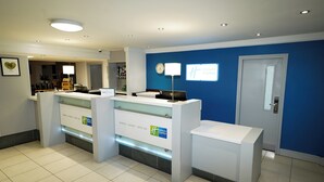 A hotel reception area with a blue wall, a clock, and a sign that reads "Holiday Inn Express." - Holiday Inn Express Leeds East by IHG (Leeds)