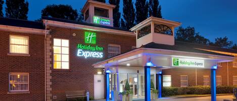 Um hotel Holiday Inn Express com fachada de tijolos, entrada coberta e estacionamento.