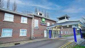 A Holiday Inn Express building with a brick facade, large windows, and a covered entrance area. - Holiday Inn Express Leeds East by IHG (Leeds)