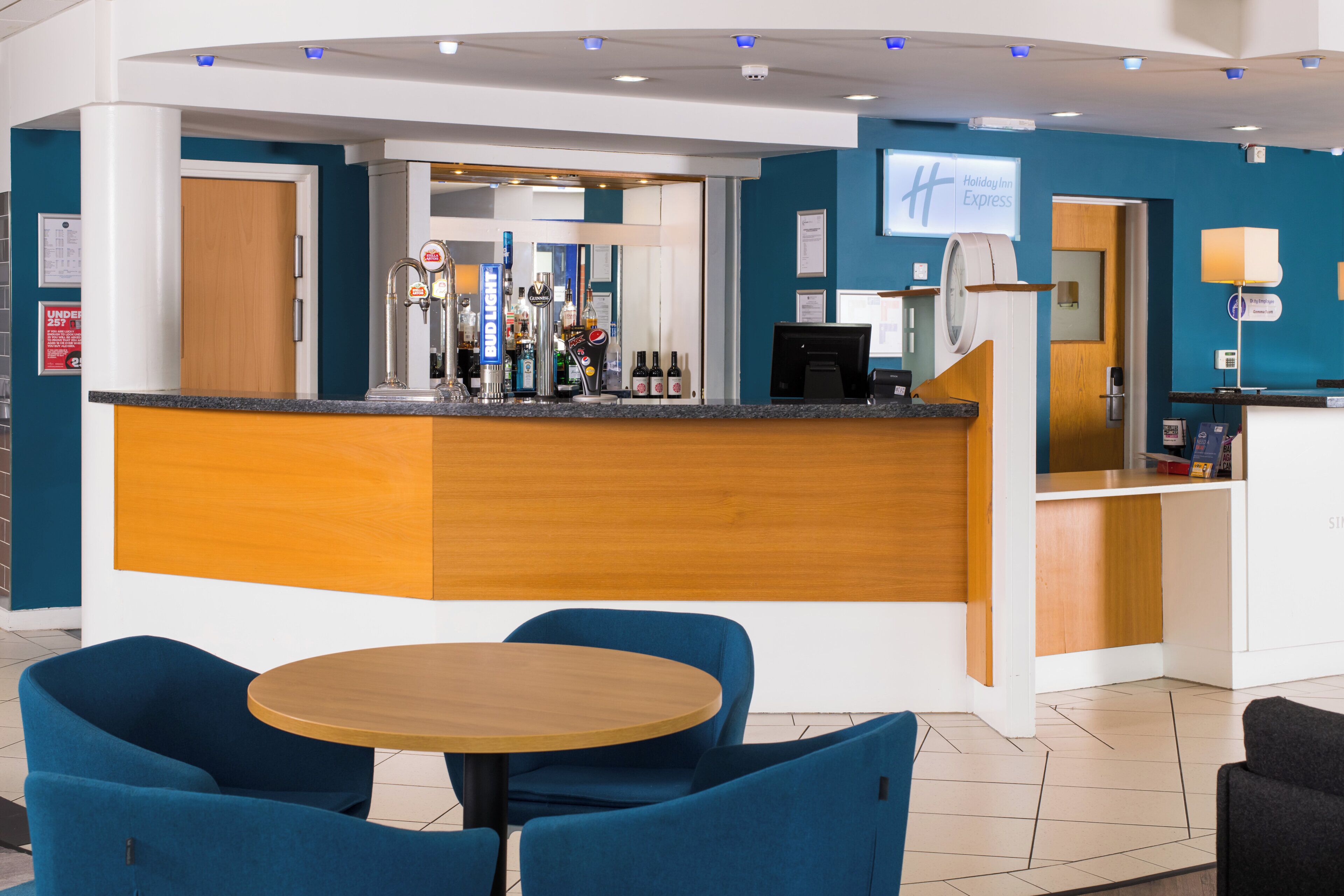 Eine Hotelhalle mit Empfangsbereich, Bar und Sitzgelegenheiten.