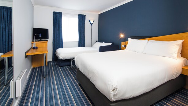 A hotel room with a large bed, two smaller beds, a desk with a computer, and a TV. - Holiday Inn Express Manchester East by IHG (Manchester)