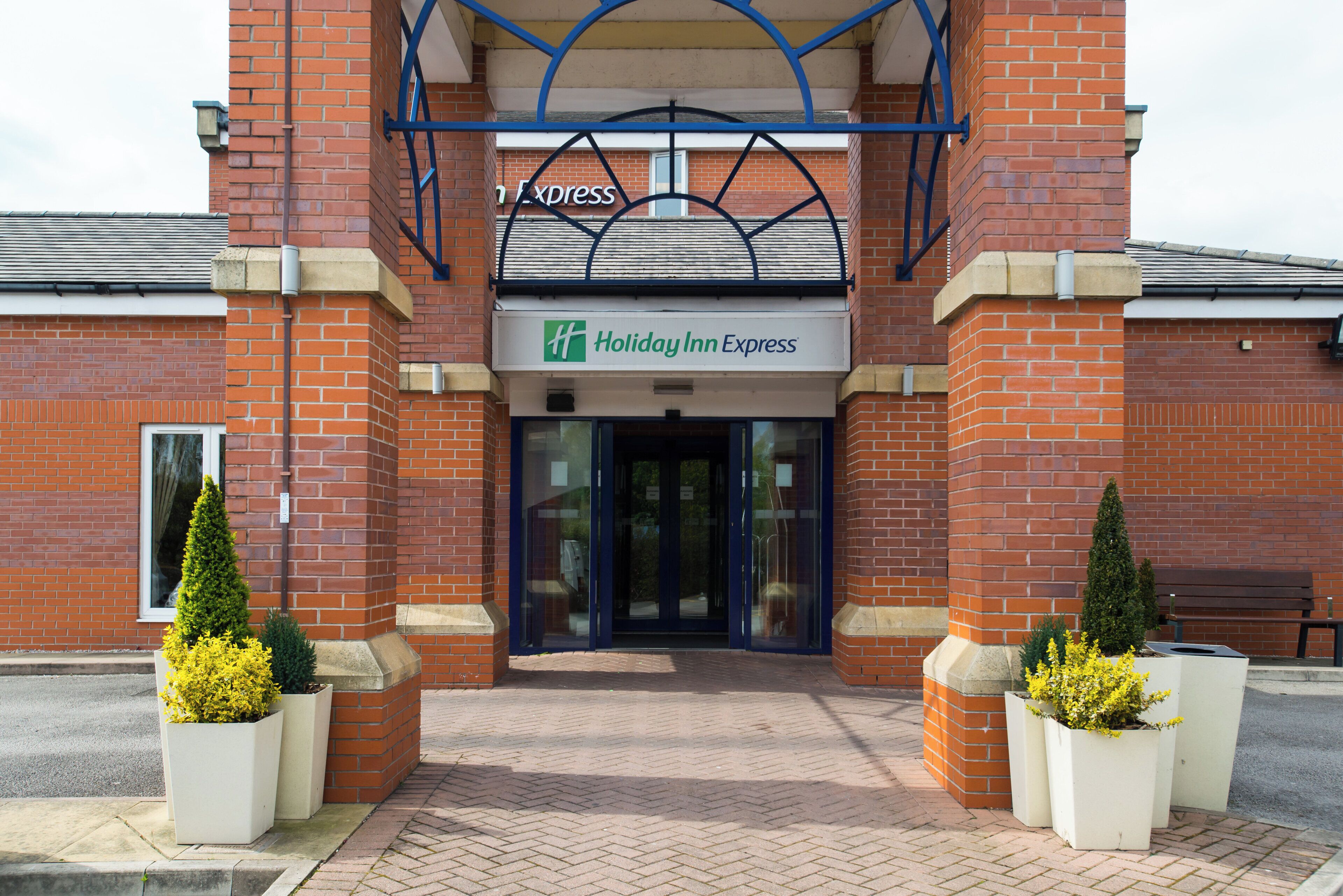 The entrance to a Holiday Inn Express with a brick facade, glass doors, and a blue awning.