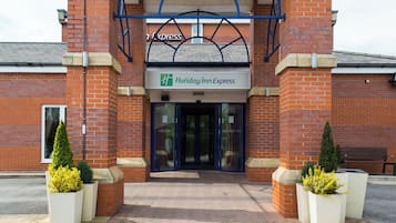 The entrance to a Holiday Inn Express with a brick facade, glass doors, and a blue awning.