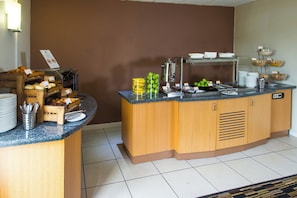 A buffet setup with various food items and utensils.
