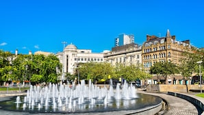 A public fountain with water jets, surrounded by historic buildings and trees. - Holiday Inn Express Manchester East by IHG (Manchester)