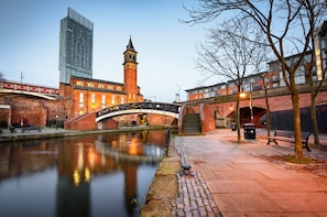 Un edificio histórico con una torre de reloj, un puente y un rascacielos moderno al fondo.