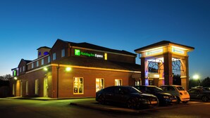 A Holiday Inn Express hotel with a parking lot and multiple cars parked in front. - Holiday Inn Express Manchester East by IHG (Manchester)