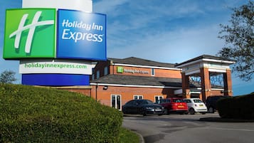 A Holiday Inn Express hotel with a prominent sign, a parking lot, and a brick building facade.