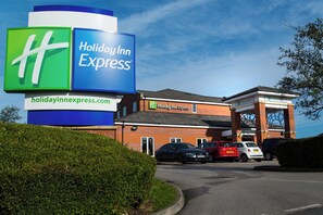 Un hotel Holiday Inn Express con un cartel llamativo, un estacionamiento y fachada de ladrillo.