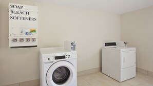 A laundry area with a washing machine, dryer, and a soap, bleach, softeners dispenser.