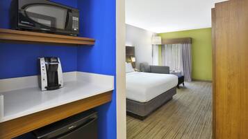 A hotel room with a bed, a desk with a microwave and a coffee maker, and a bathroom.