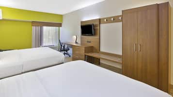 A hotel room with two beds, a desk, a chair, a television, and a wardrobe.