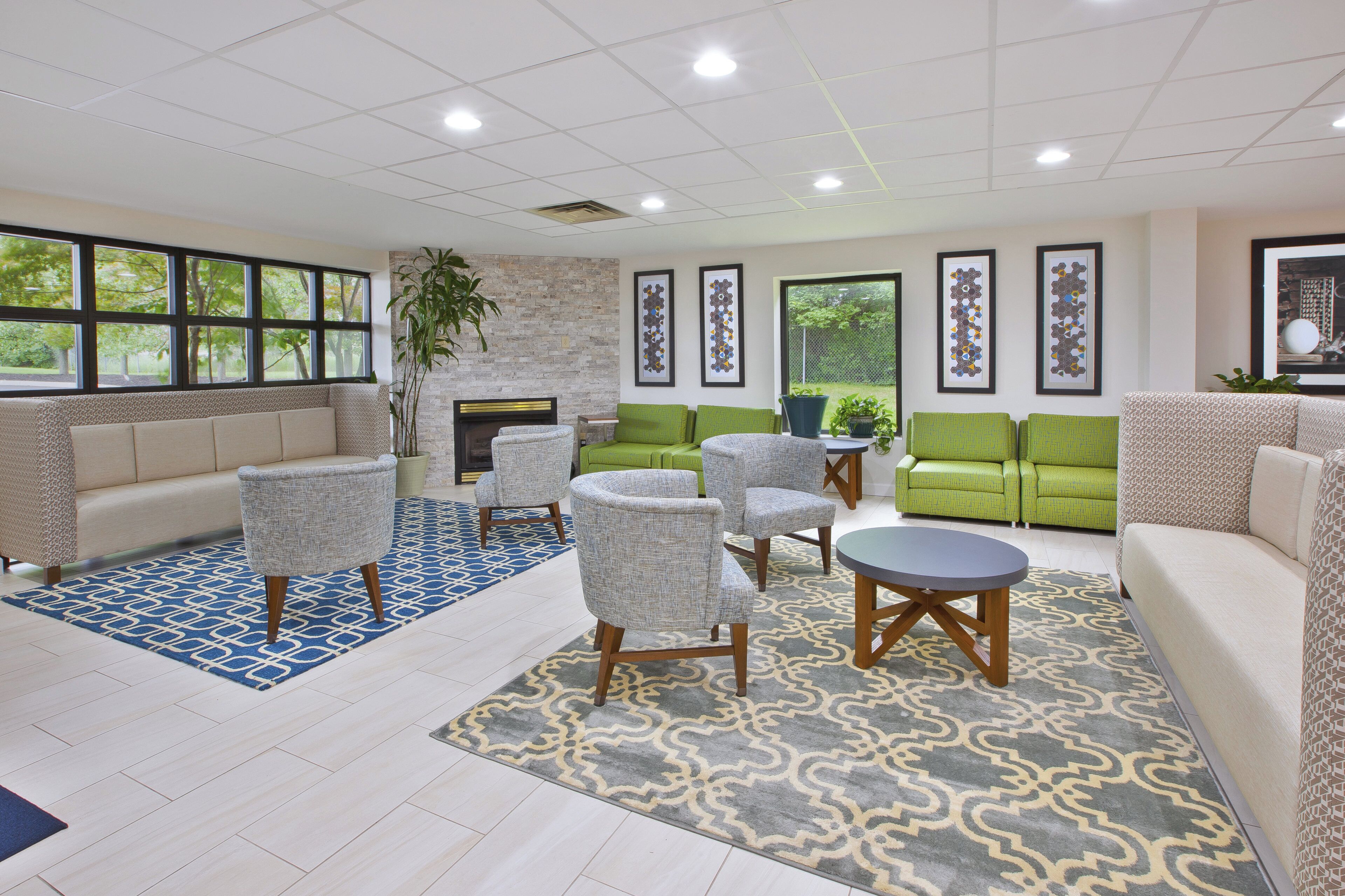 A spacious lounge area with a fireplace, multiple seating options including sofas and chairs, and a large window providing a view of the outdoors.