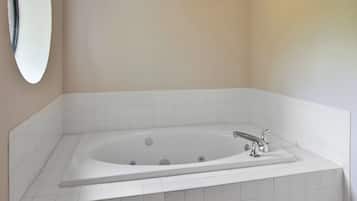 A bathroom with a freestanding bathtub, white tiles, and a wall-mounted mirror.