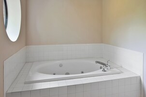 A bathroom with a freestanding bathtub, white tiles, and a wall-mounted mirror.
