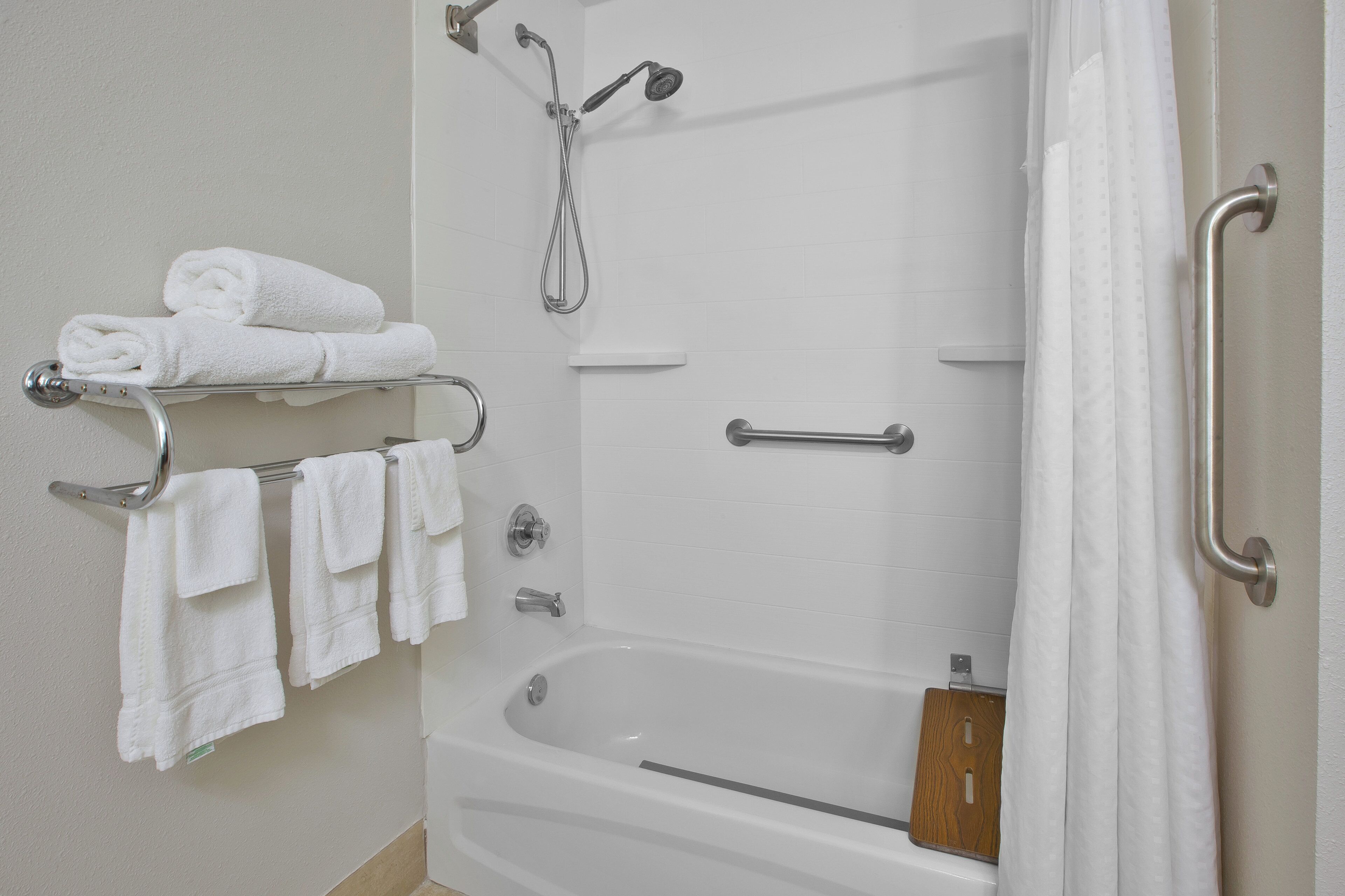 A bathroom with a bathtub, a shower, and a towel rack with folded towels.