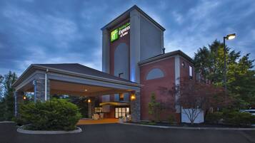 A Holiday Inn Express & Suites hotel with a prominent tower and a covered entrance.