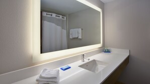 A modern bathroom with a large mirror, a sink, and a towel rack.
