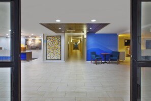 A hotel lobby with a long corridor, a reception desk, and seating area.