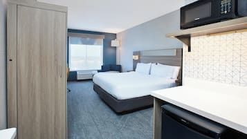 A hotel room with a bed, a desk, a microwave, and a wardrobe.
