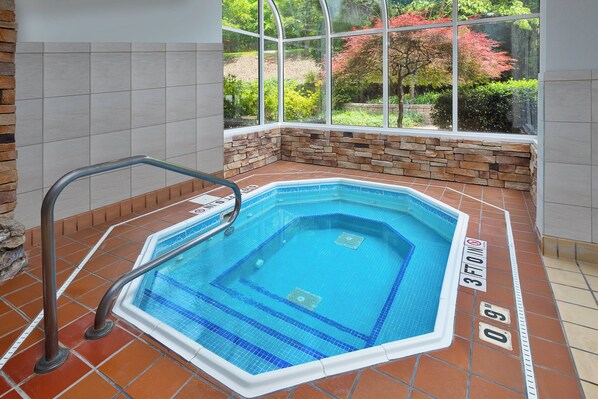 A hot tub with a stone wall and a window overlooking a garden. - Holiday Inn Express & Suites Youngstown N (Warren/Niles) by IHG (Warren)