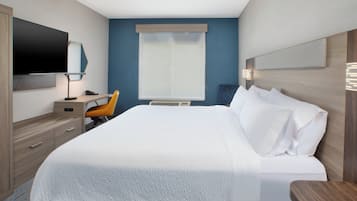 Ein Hotelzimmer mit einem Bett, einem Schreibtisch, einem Sessel, einem Fernseher und einem Fenster.