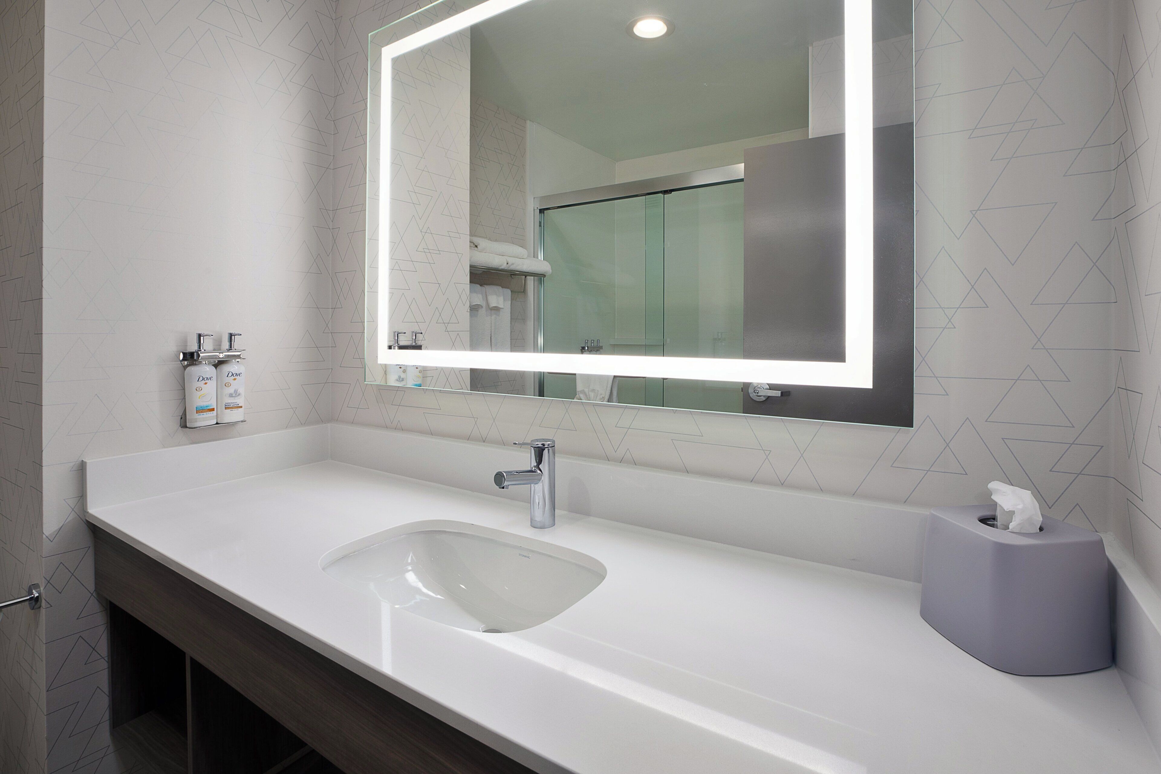 A modern bathroom with a white sink, a mirror, and a towel rack.