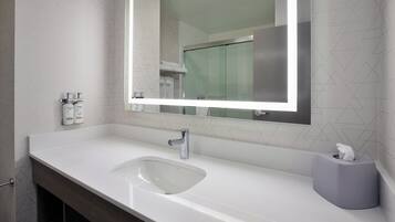 A modern bathroom with a white sink, a mirror, and a towel rack.
