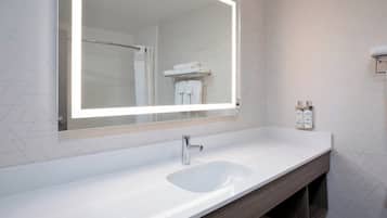 A bathroom with a large mirror, a sink, and a towel rack.