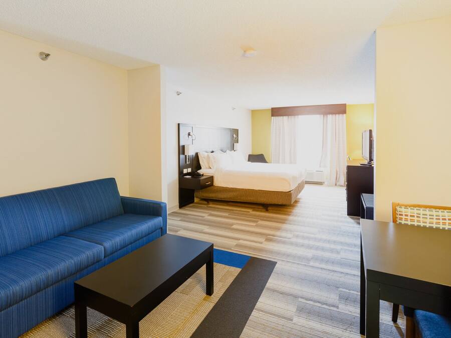 Een hotelkamer met een blauwe bank, een bed met een witte dekbedovertrek, een bureau met een stoel en een televisie.