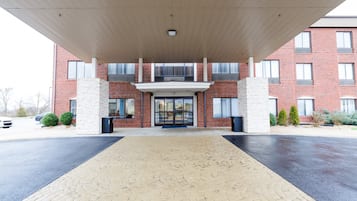 Fachada de edificio de ladrillo con una galería techada y grandes ventanales.