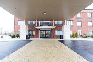 A building entrance with a covered walkway, brick facade, and large windows.