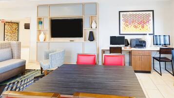 A modern living room with a flat-screen TV, a dining table with red chairs, a sofa, and a patterned rug.